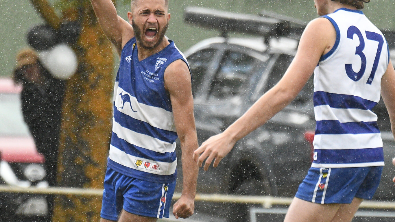 A Mount Barker player celebrating a goal in the rain during a Hills Football League match
