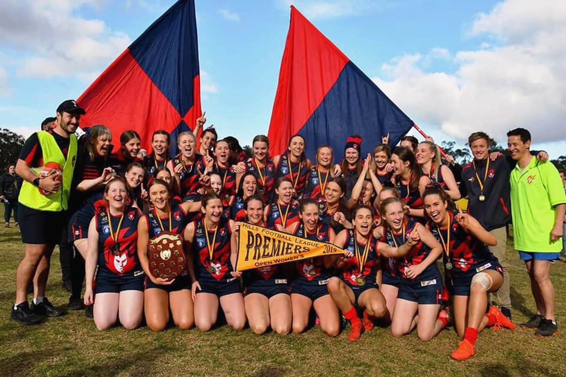 The 2019 HFL Open Women's premiership team celebrating with the shield and flags