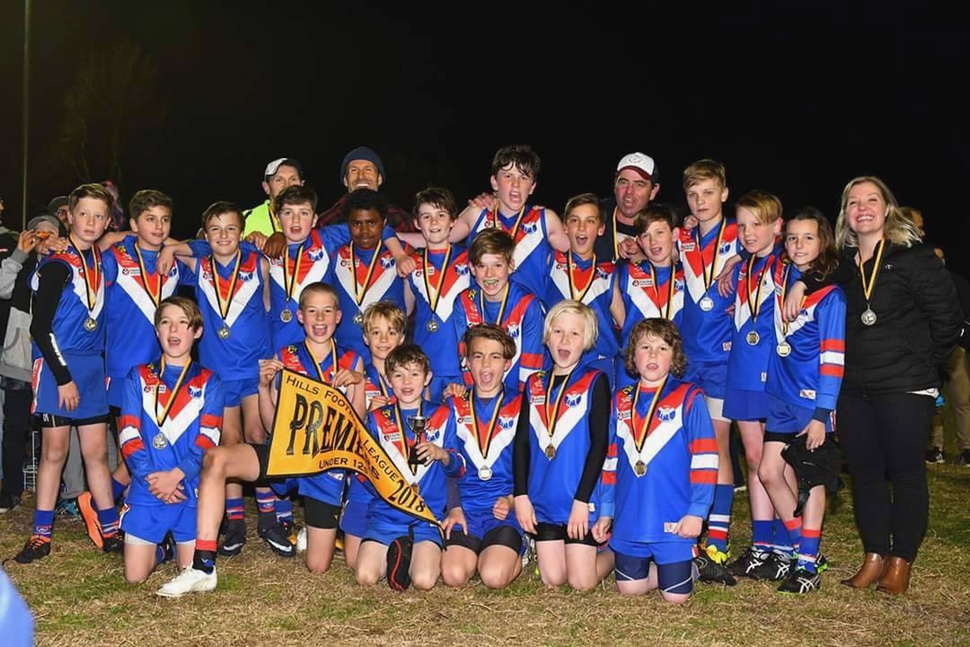 The 2018 HFL Under 12s premiership team celebrating with medals and the premiership flag
